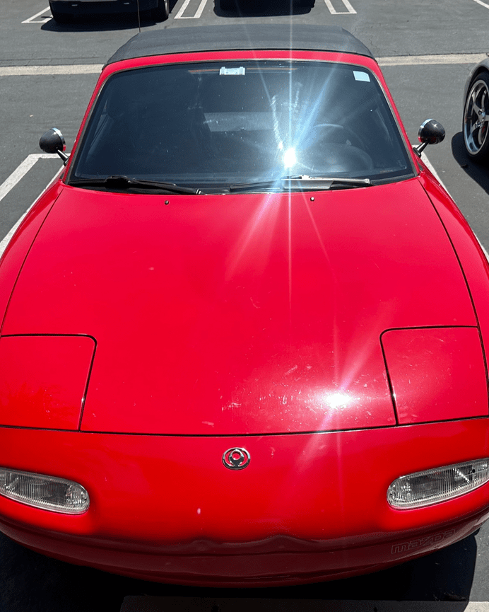 Red 1990 Mazda Miata with worn black convertible top before replacement at The Prestige Companies Auto Upholstery in Anaheim, Orange County, CA